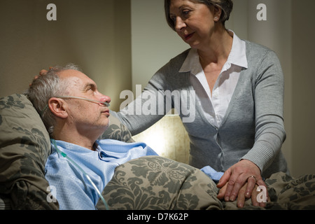 Worried senior woman caring with sick husband in the bedroom Stock Photo