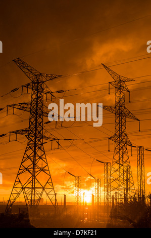High-voltage power transmission towers in sunset sky background Stock ...