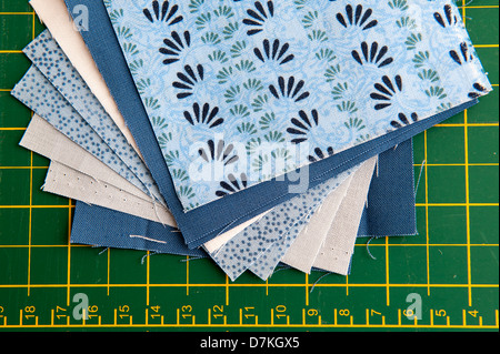 Quilting or patchwork materials on a green measuring board showing blue and white patterned fat quarters Stock Photo