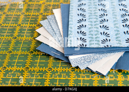 Quilting or patchwork materials on a green measuring board showing blue and white patterned fat quarters Stock Photo