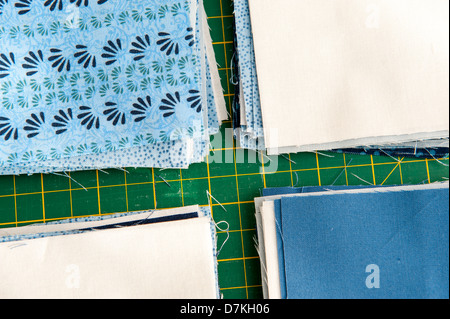 Quilting or patchwork materials on a green measuring board showing blue and white patterned fat quarters Stock Photo