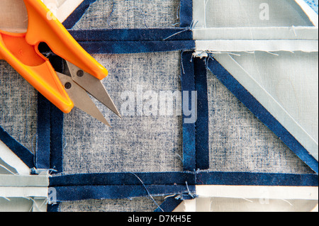 Quilting or patchwork materials and tools with scissors showing blue and white patterned fat quarters green cutting mat with yellow grid Stock Photo