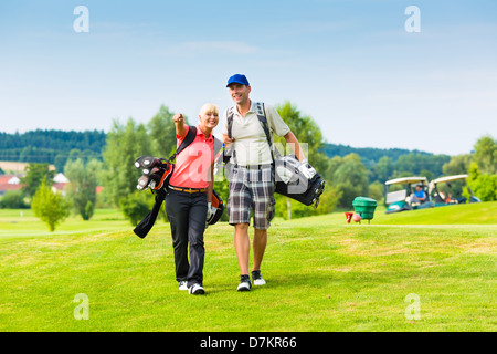 Young sportive couple playing golf on a golf course, they walking to the next hole Stock Photo