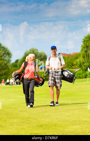 Young sportive couple playing golf on a golf course, they walking to the next hole Stock Photo