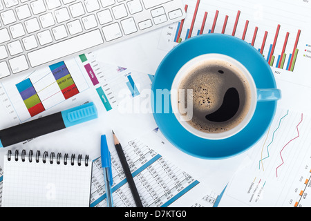 Blue coffee cup on financial papers, computer and office supplies Stock Photo