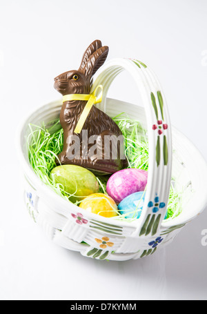 Easter eggs and a Chocolate Rabbit in a ceramic basket. Holiday Traditions Stock Photo