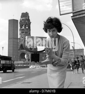 This woman presents a very valuable clock, on 2 June 1963 in front of the memorial church in Berlin, which will be given to US president John F. Kennedy as a guest present during his imminent visit. Stock Photo