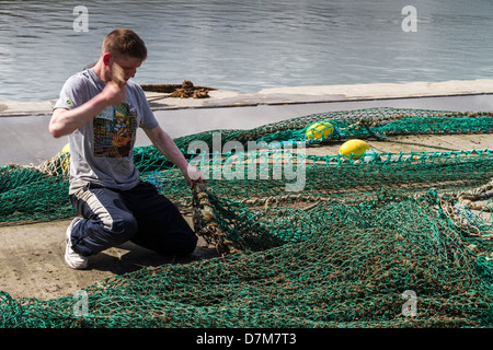 Nets being mended and prepared prior to fishing trip Stock Photo