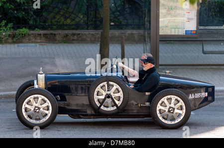 2 men driving a black Bugatti French vintage car Stock Photo