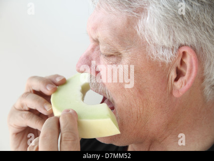 senior man eats fresh melon Stock Photo