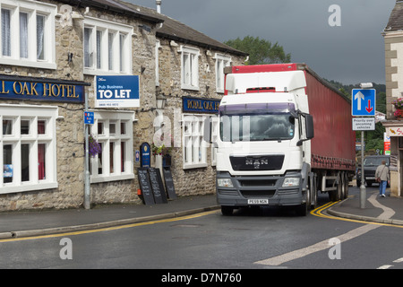 An articulated lorry (HGV) negotiating the narrow road (B6480) which passes through the town centre of Settle in North Yorkshire Stock Photo