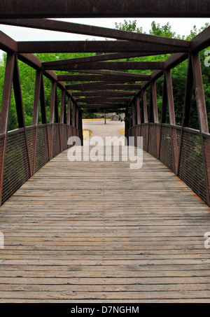 Arcing wood and metal frame bridge in park. Stock Photo