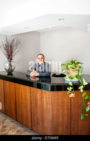 Businessman standing at reception counter in office Stock Photo