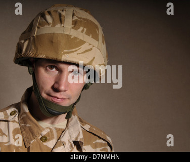 Portrait of a soldier with  blank expression on his face against a dark background. Soldier is wearing British Military uniform. Stock Photo