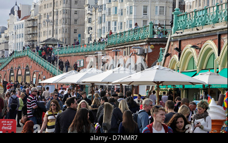 PEOPLE WALKING ALONG BRIGHTON BEACH SEAFRONT ON SUNNY DAY, APRIL 2013 Stock Photo