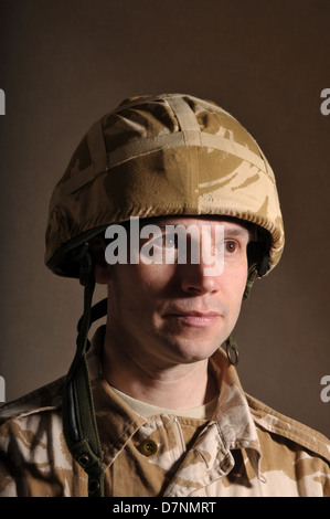 Portrait of a soldier with  blank expression on his face against a dark background. Soldier is wearing British Military uniform. Stock Photo