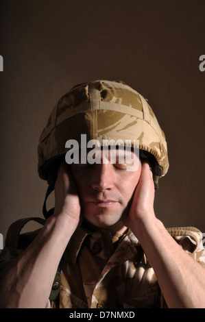 Soldier with his eyes closed and hands covering his ears. Soldier is ...