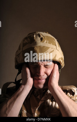 Soldier with his eyes closed and hands covering his ears. Soldier is ...