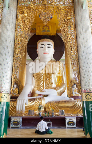 Man praying to large seated Buddha at the Shwedagon Pagoda in Yangon, Myanmar 2 Stock Photo