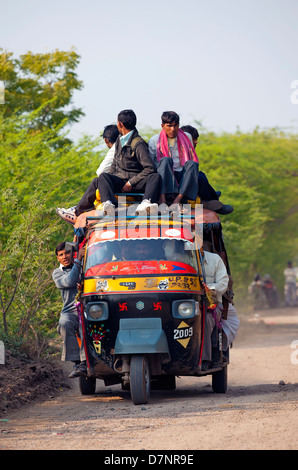 An overloaded three-wheeler auto rickshaw with local people travelling ...