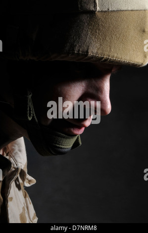 Shell shocked soldier in shadow. Soldier is wearing British Military desert camouflage uniform. Stock Photo