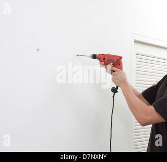 a man using an electric screwdriver with empty space on the wall Stock Photo