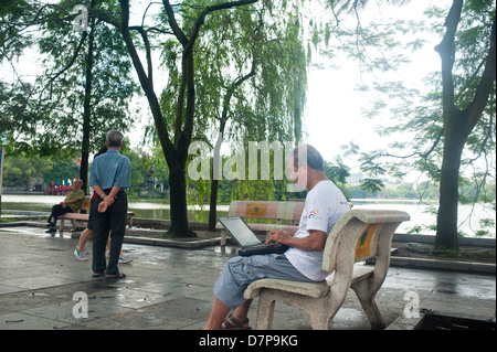 Vietnam, Hanoi, Lenin Park - Elderly man using laptop at Lenin park Stock Photo