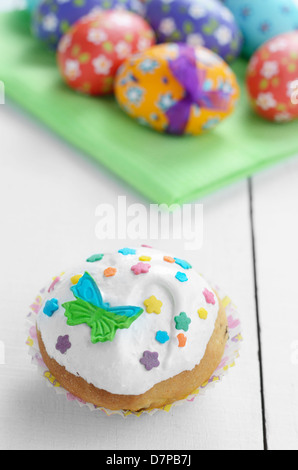 Easter treat - cupcake and eggs with painted flowers on white table Stock Photo