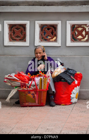 Vertical portrait of an old blind lady on a mobile phone near the Ngoc Son Temple or Jade Mountain temple in Hanoi. Stock Photo