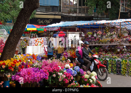 Horizontal close up of the colourful flower market stalls selling arrangements in baskets and bouquets for Tet, Vietnamese New Year. Stock Photo