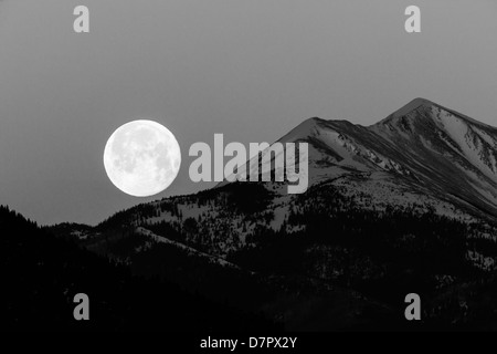 Black and white view of full moon setting over Rocky Mountains, Salida, Colorado, USA Stock Photo