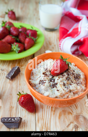 oatmeal in a bowl with milk and strawberries, breakfast closeup Stock Photo