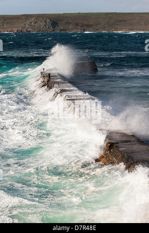 Rough seas crashing over the breakwater at Sennen in Cornwall. Stock Photo