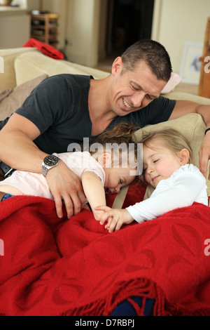 Father playing with his daughters in their makeshift bed on the couch in the living room. Stock Photo