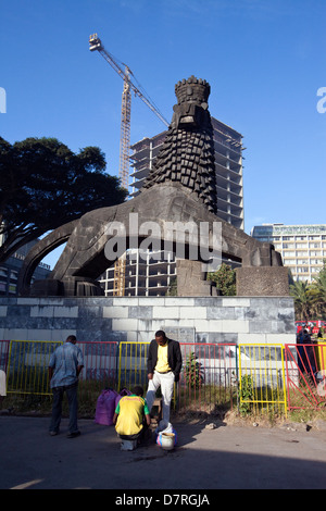 A man has his shoes shined beneath a Lion of Judah statue outside the National Theatre, Addis Ababa, Ethiopia. Stock Photo