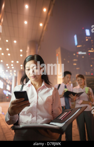Young businesswoman with her cell phone, coworkers on the background, portrait Stock Photo