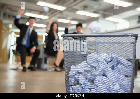 Three coworkers preparing to throw paper into waste basket Stock Photo