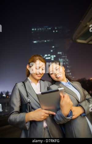 Young businesswomen looking at digital tablet and walking Stock Photo