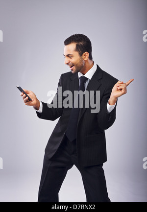 Young businessman with phone dancing out of joy Stock Photo