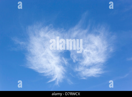 White cloud in the shape of a heart or angel's wings in bright blue sky. Stock Photo