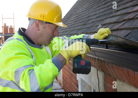 Builder working on a roof installing guttering Stock Photo