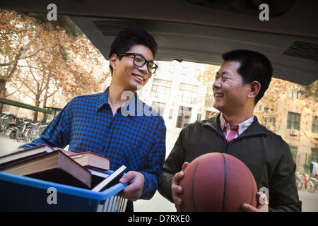 Father and Son in back of car in front of dormitory Stock Photo