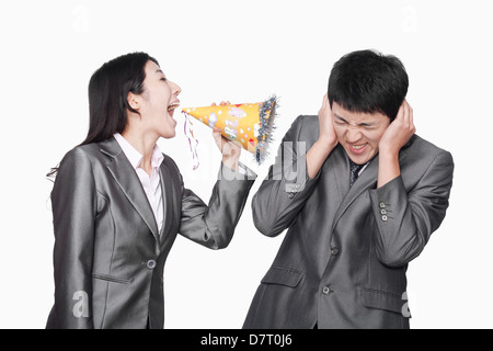 Businesswoman yelling at her colleague through party hat Stock Photo