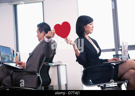 Work romance between two business people holding a heart Stock Photo