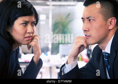 Two Business people staring at each other across a table Stock Photo