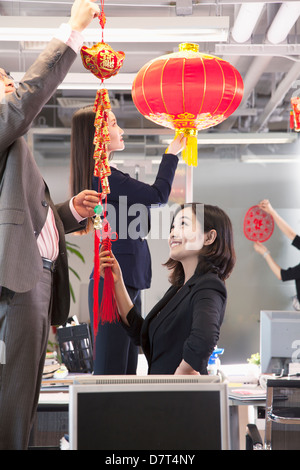 Coworkers hanging decorations in office for Chinese new year Stock Photo