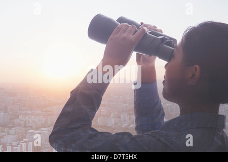 Double exposure of young businesswoman holding binoculars over cityscape of Beijing Stock Photo