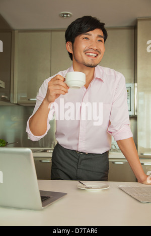 Businessman in front of his computer drinking coffee at home Stock Photo