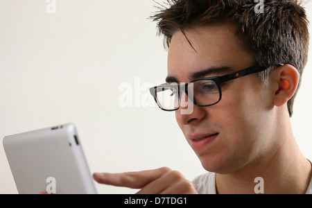 Young male adult wearing glasses using a digital tablet. Stock Photo