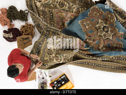 An overhead view of an Oriental rug being repaired. A studio photo on a white background. Stock Photo